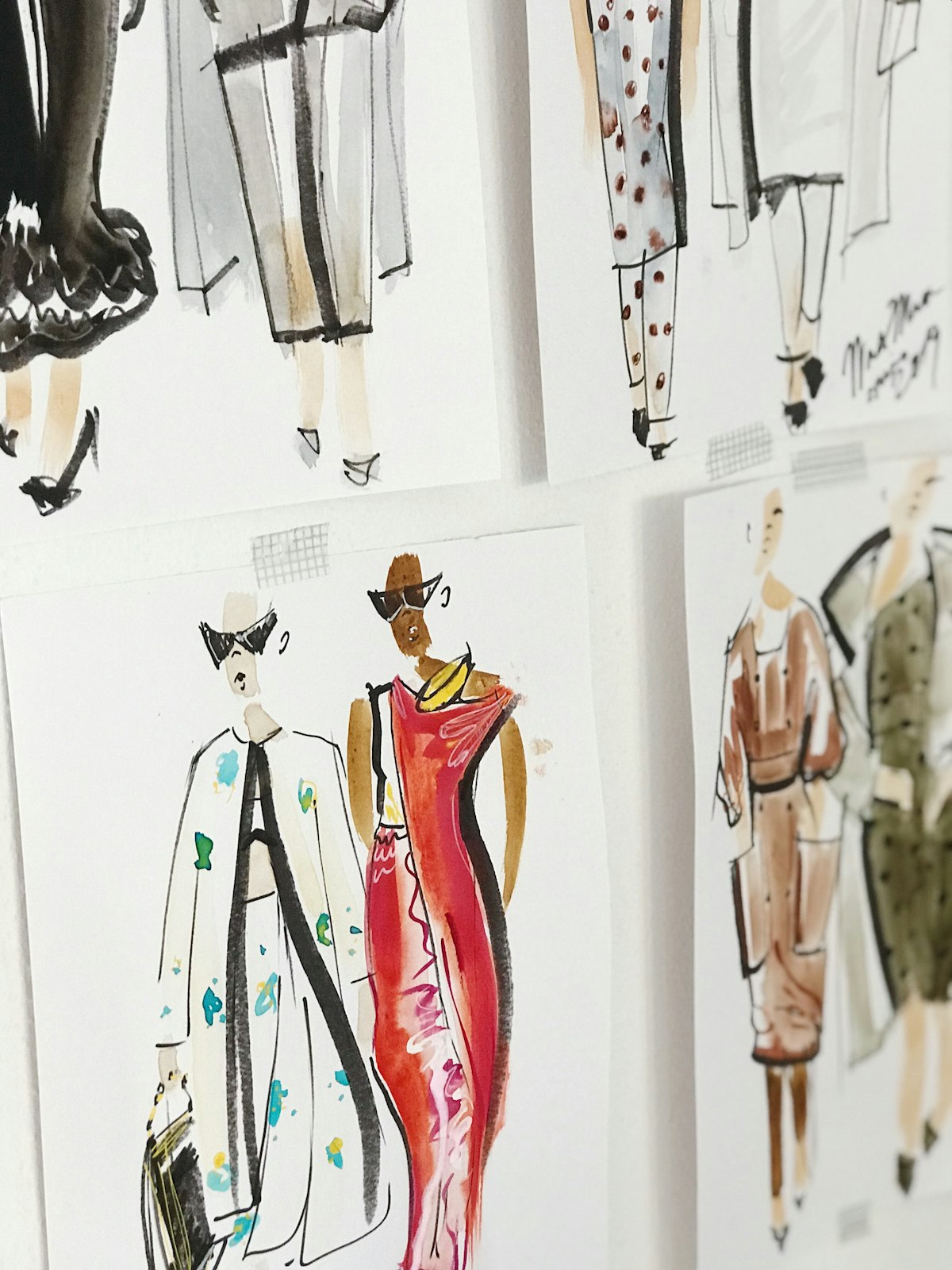 Fashion sketches pinned to a studio wall with grid tape